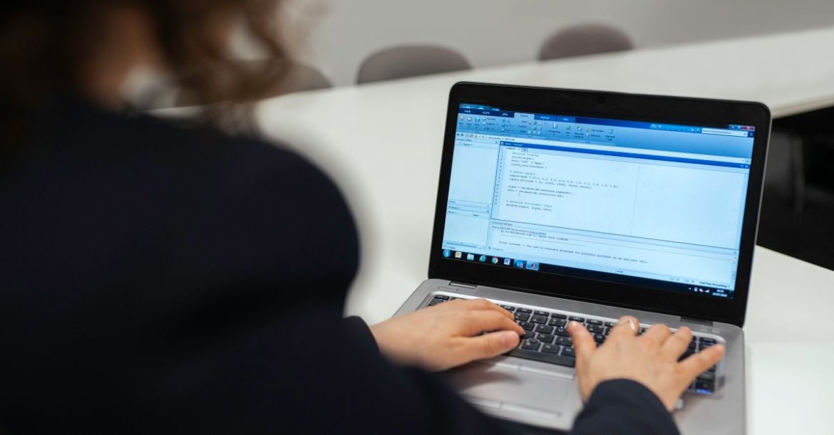 Developer coding on a laptop in an office, illustrating the Amazon Q developer vulnerability risk when opening cloned repositories in VS Code