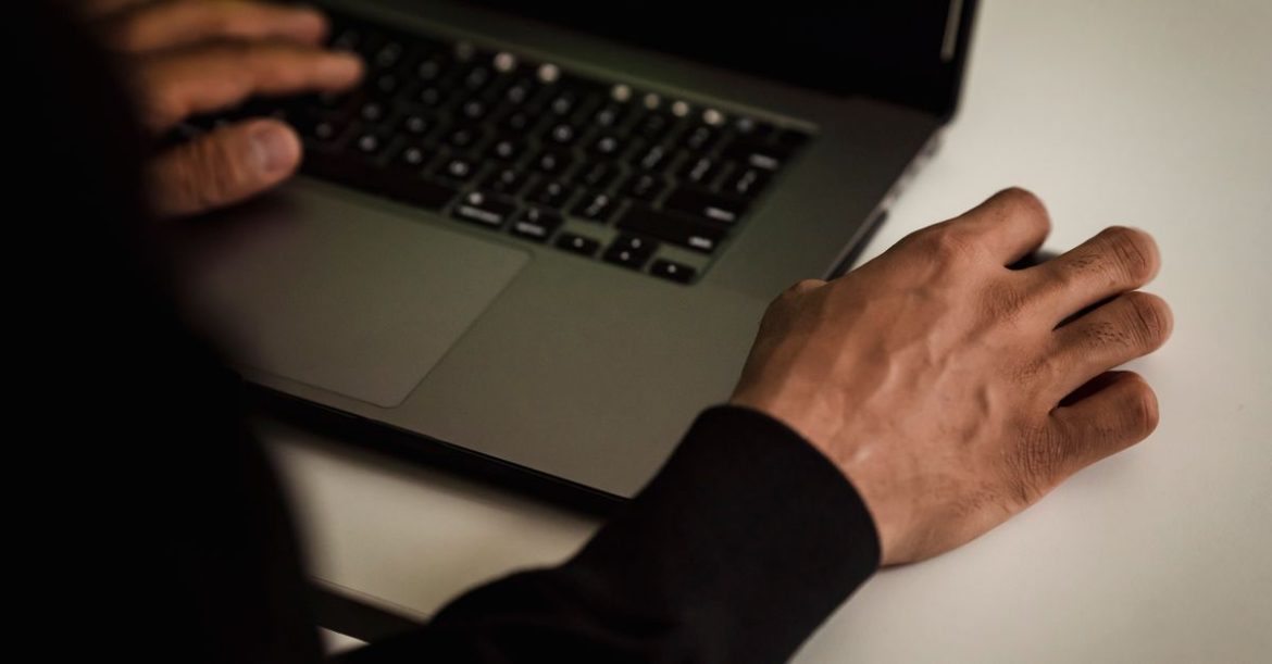 Close-up of hands typing on a laptop in a dim room, investigating the Bing Images RCE flaws