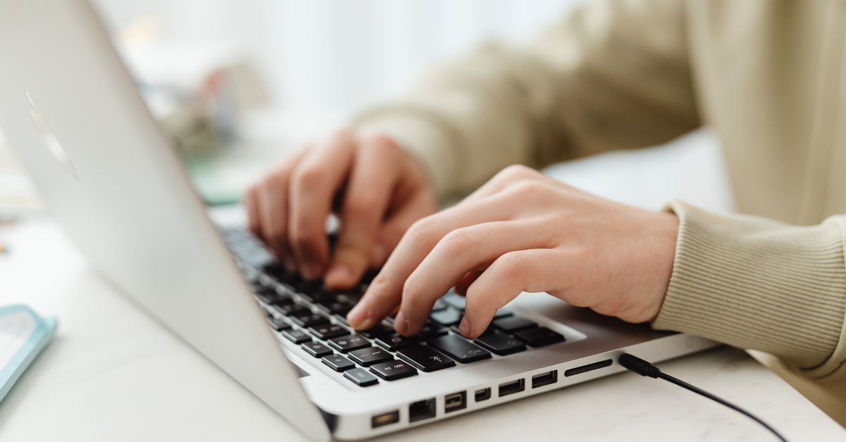 Close-up of hands typing on a laptop keyboard, representing the browser session msaRAT Chaos ransomware hijacks for C2