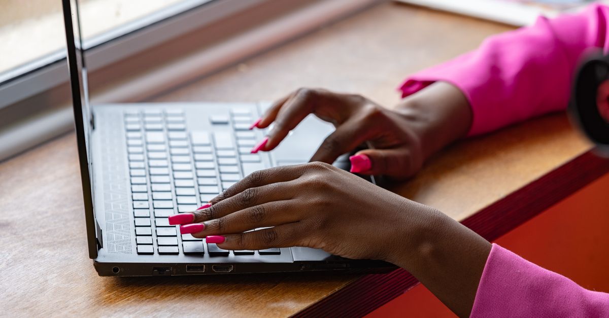Close-up of hands typing on a laptop keyboard while checking a patch status