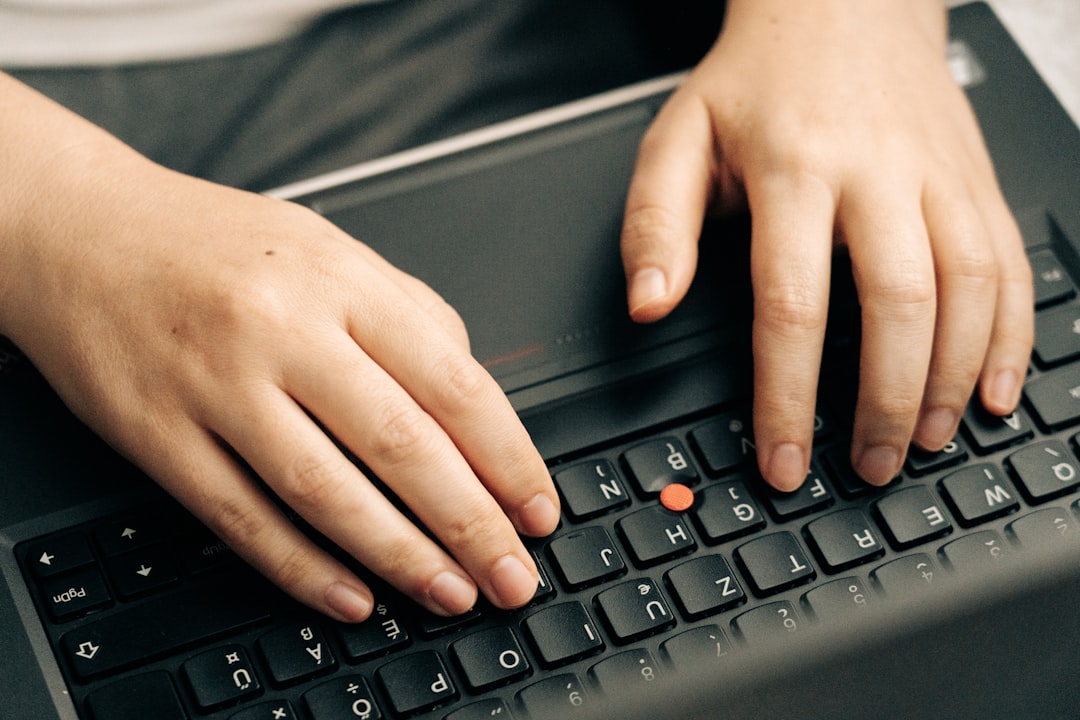 Close-up of hands typing on a laptop keyboard while testing for a CORS misconfiguration vulnerability